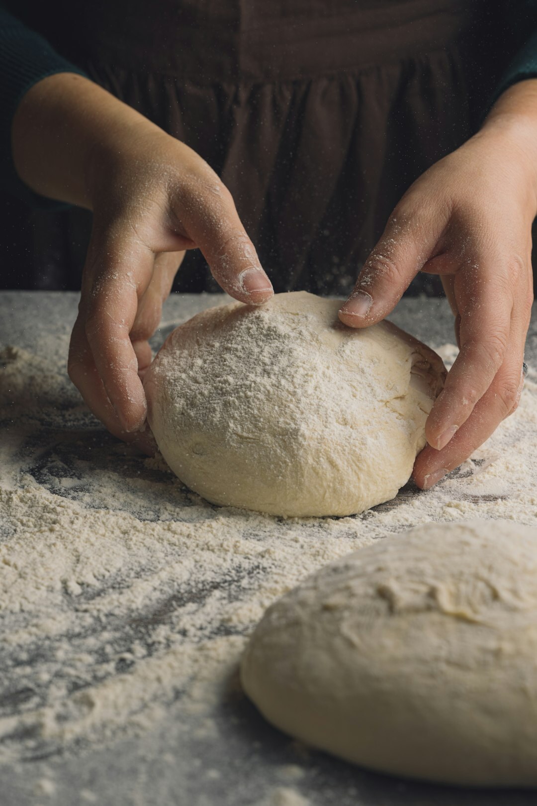 Hands kneading dough for traditional Czech buchty on a floured wooden table